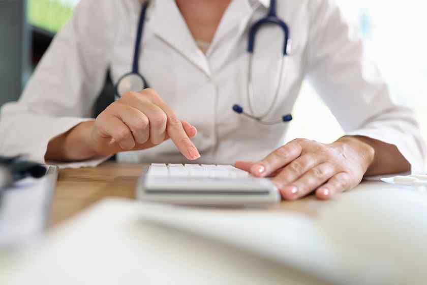 Foto: Ärztin arbeitet auf Taschenrechner im Büro